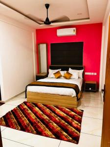 a bedroom with a large bed with a red wall at Nice Inn Residency in Kozhikode