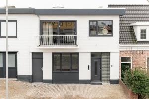 a white house with black doors and a balcony at Slapen bij van O 2 in Yerseke
