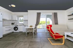 a kitchen and living room with a couch and a red chair at Muskebi Apart Otel in Ortakent