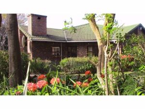 ein Backsteinhaus mit Blumen davor in der Unterkunft Forest Nest Cottage, Tsitsikamma in Stormsrivier