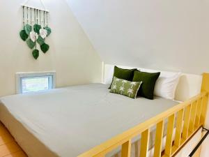 a bedroom with a bed with green and white pillows at Tiny Secret in Ban Tai