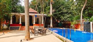 a pool with chairs and a table next to a house at Sun Private Pool Villa in Puducherry Airpoert
