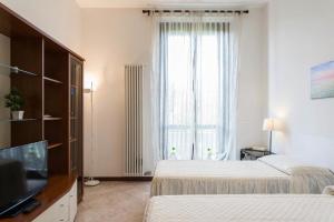 a bedroom with two beds and a tv and a window at Appartamento Via Rovetta in Milan