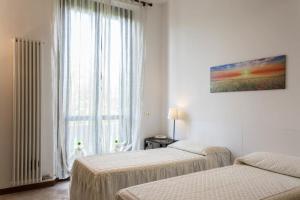 2 Betten in einem weißen Zimmer mit Fenster in der Unterkunft Appartamento Via Rovetta in Mailand
