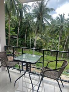 a table and chairs on a balcony with palm trees at Mina House in Thong Nai Pan Yai +3 photos