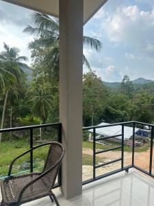 a balcony with a chair and a view of the forest at Mina House in Thong Nai Pan Yai