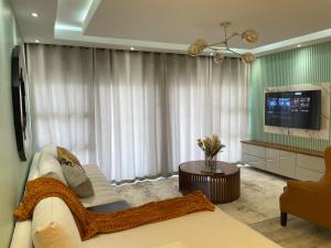 a living room with a white couch and a tv at Muyeni BnB in Harare
