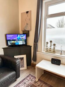 a living room with a couch and a tv and a window at Comfortable rooms Manchester in Manchester