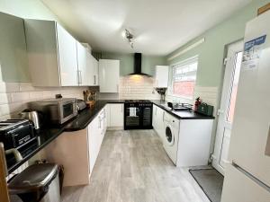 a kitchen with white cabinets and black counter tops at Comfortable rooms Manchester in Manchester