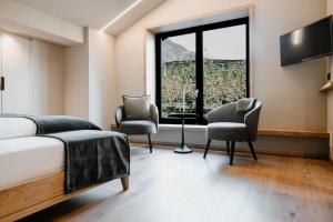 a bedroom with a bed and two chairs and a window at Stricker Aparthotel in Tirolo