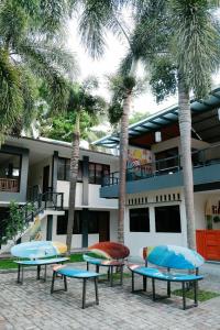three picnic tables in front of a building with palm trees at Hau Batu Karas in Batukaras