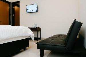 a bedroom with a bed and a black leather chair at Hau Batu Karas in Batukaras