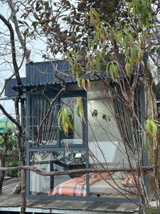 a house with a blue window and a tree at Vuon Hong Le Phuc-Cau Dat Glamping Retreat Da Lat in Ấp Trạm Hành