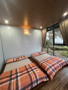 two beds in the corner of a room with windows at Vuon Hong Le Phuc-Cau Dat Glamping Retreat Da Lat in Ấp Trạm Hành