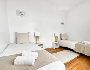 two beds in a room with white walls and wooden floors at Superbe T3 familial et rénové au cœur de la ville - Proche Paris in Alfortville