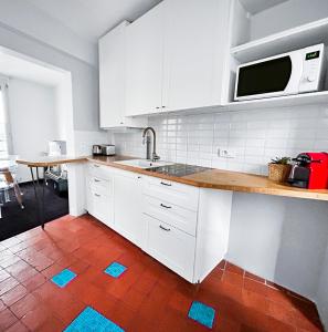 a kitchen with white cabinets and a red tile floor at Superbe T3 familial et rénové au cœur de la ville - Proche Paris in Alfortville