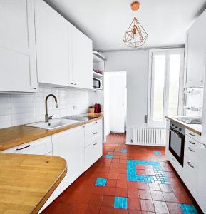 a kitchen with white cabinets and a red tile floor at Superbe T3 familial et rénové au cœur de la ville - Proche Paris in Alfortville +11 photos
