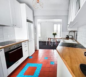 a kitchen with white cabinets and a red tile floor at Superbe T3 familial et rénové au cœur de la ville - Proche Paris in Alfortville