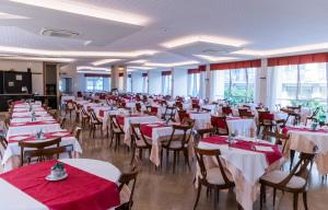 a banquet hall with tables and chairs with red tablecloths at Hotel President in Alba Adriatica