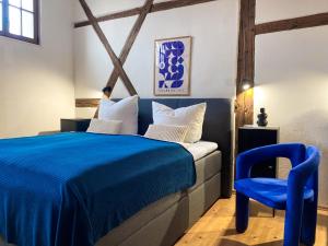 a bedroom with a blue bed and a blue chair at WEINQUARTIER Naumburg 6 Apartments Eventraum Fahrradraum Kaffee Küche Parken in Naumburg