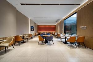 a dining room with tables and chairs and windows at Echarm International Hotel Guangzhou Huangpu Flagship Shuixi Subway Station Branch - Free Deliver Service to Guangzhou Baiyun International Airport & Free Deliver Service to Canton Fair Complex During Canton Fair Period in Guangzhou