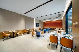 a restaurant with tables and chairs in a room at Echarm International Hotel Guangzhou Huangpu Flagship Shuixi Subway Station Branch - Free Deliver Service to Guangzhou Baiyun International Airport & Free Deliver Service to Canton Fair Complex During Canton Fair Period in Guangzhou