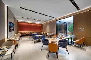 a restaurant with tables and chairs and windows at Echarm International Hotel Guangzhou Huangpu Flagship Shuixi Subway Station Branch - Free Deliver Service to Guangzhou Baiyun International Airport & Free Deliver Service to Canton Fair Complex During Canton Fair Period in Guangzhou