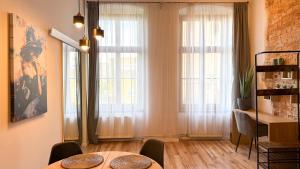 a dining room with a table and two large windows at Zapisane w Cegle by LibertaRent in Świdnica