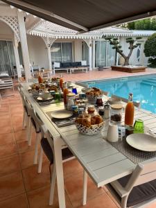a table with food on it next to a pool at Chambres d'Hôtes Villa La Louisiane in Arès