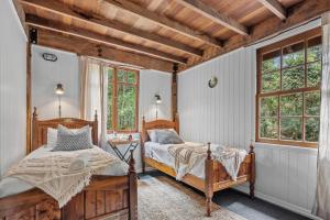 a bedroom with two beds and two windows at Rustic 3-Bed Retreat in Springbrook in Springbrook +9 photos