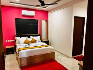 a bedroom with a large bed with a red wall at Nice Inn Residency in Kozhikode