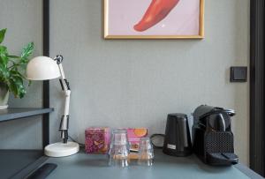 een bureau met een lamp en een koffiezetapparaat erop bij The Saints Sutor Hotel in Breda