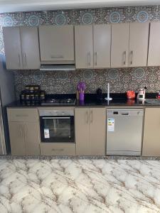 a kitchen with white cabinets and a patterned wall at Villa haut standing vue mere in Kenitra +18 photos