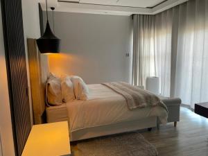 a bedroom with a bed with white sheets and a lamp at Muyeni BnB in Harare