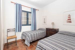 a bedroom with two beds and a chair and a window at GuestReady - Marea La Graciosa relax para familias in Caleta de Sebo