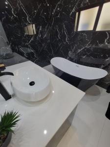 a bathroom with a white sink and a black wall at Muyeni BnB in Harare +18 photos
