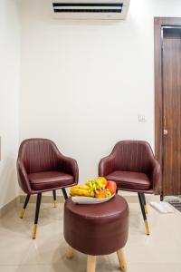two chairs and a bowl of fruit on a stool at Hotel Delhi 53 Near ISBT Kashmiri Gate in Delhi