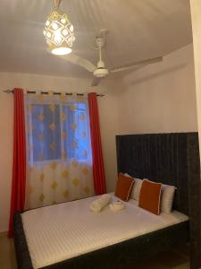 a bedroom with a bed with orange curtains and a window at Zuribreezhomes in Bamburi