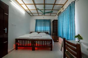 a bedroom with a bed with blue curtains and a ceiling at Backwater Home in Kumarakom +3 photos