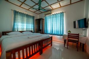 a bedroom with a large bed and a table with a chair at Backwater Home in Kumarakom