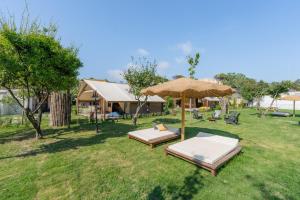 a yard with two beds and an umbrella at Procida Camp & Resort - Ciraccio in Procida
