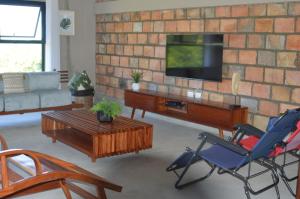 a living room with a tv on a brick wall at lodge3a in Ponta do Ouro