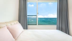 a bedroom with a bed and a window with the ocean at GoSeong Beach Jin Spa Pension in Goseong