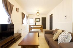 a living room with a couch and a coffee table at Sunstone GINOWAN 1F in Futemma