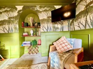 a room with green walls with a couch and a tv at Style 3BR House Jameston | Garden | Near Tenby in Tenby
