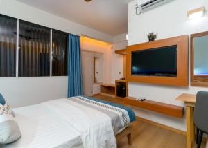 a bedroom with a bed and a flat screen tv at Rivethi Veyli Ukulhas in Ukulhas