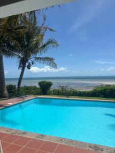a swimming pool with the ocean in the background at Paradise Beach House in Vilanculos