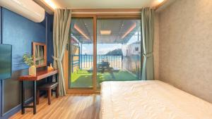 a bedroom with a bed and a sliding glass door at Goseong CNBLUE Oceanview Pension in Goseong