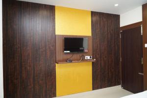 a room with a yellow and brown wall with a tv at DD COZY INN sntower in Tiruchirappalli