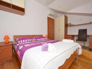 a bedroom with a large bed with purple and white sheets at Apartment Franka in Kaštela